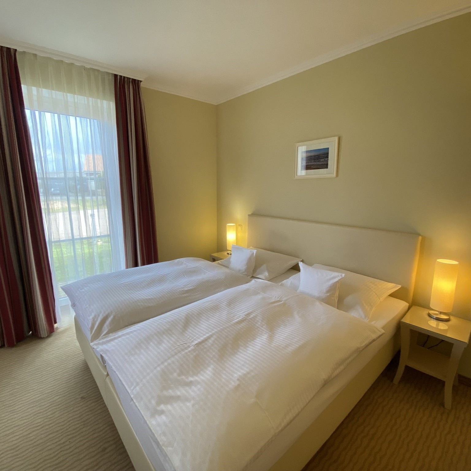 Hotelzimmer mit roten Vorhängen und Doppelbett. 