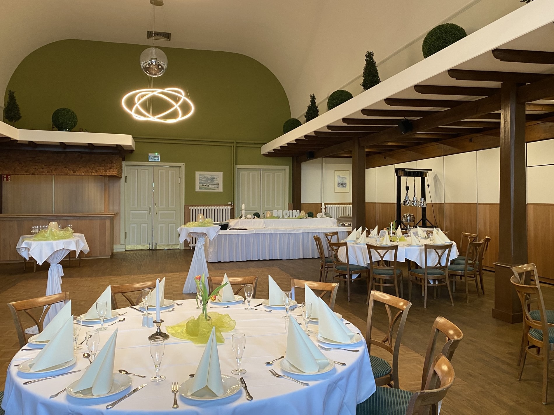Veranstaltungssaal mit eigedeckten runden Tischen.
