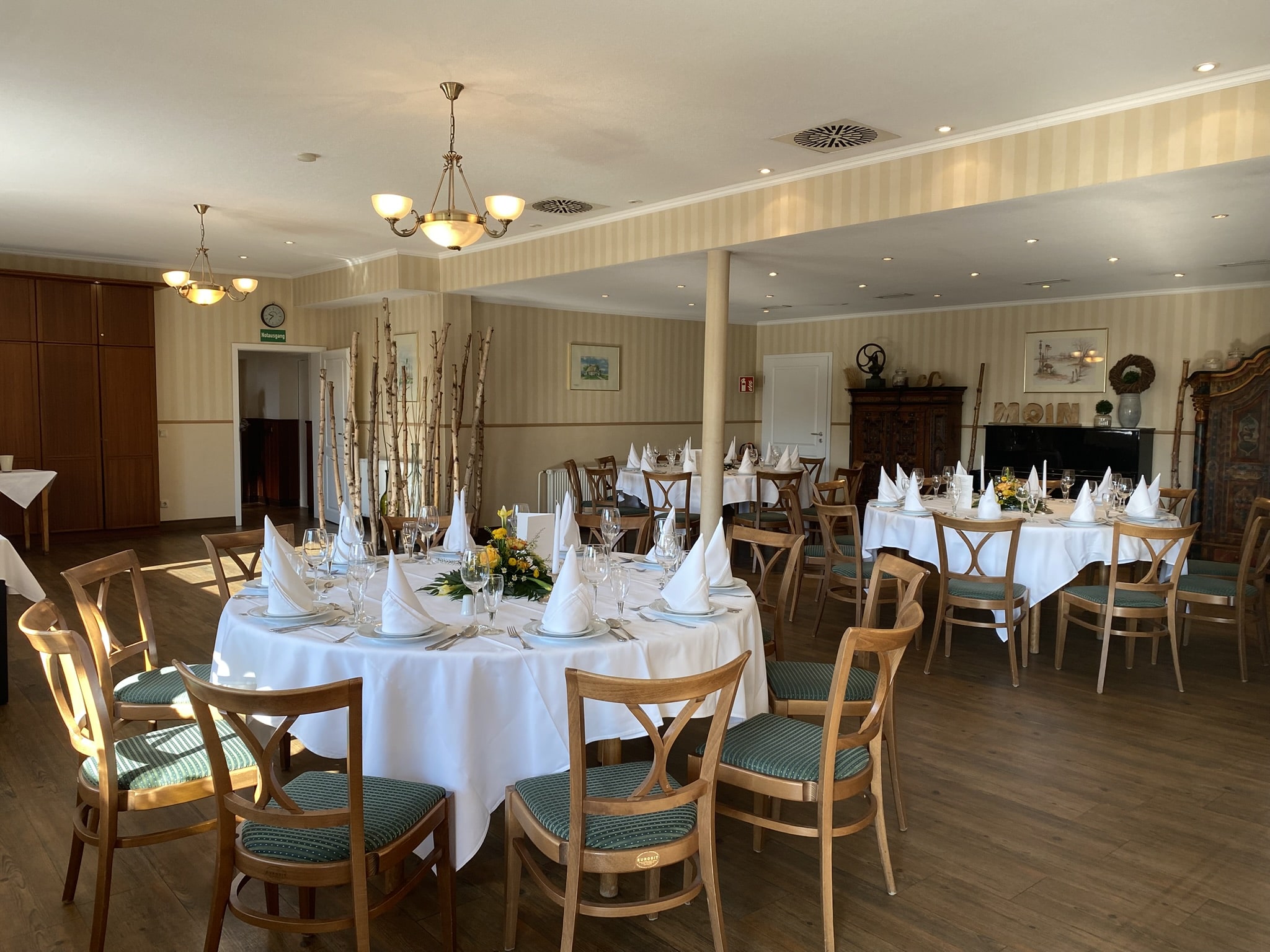 Mittlerer Veranstaltungsraum mit drei eingedeckten Tischen.